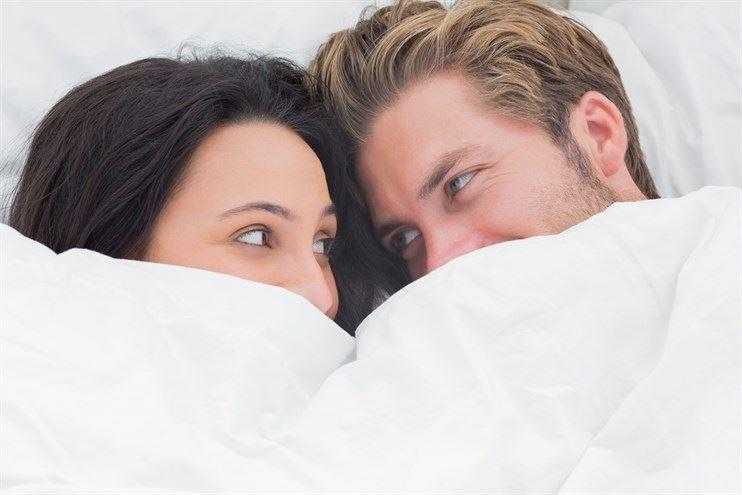 man and a woman laying on a bed 